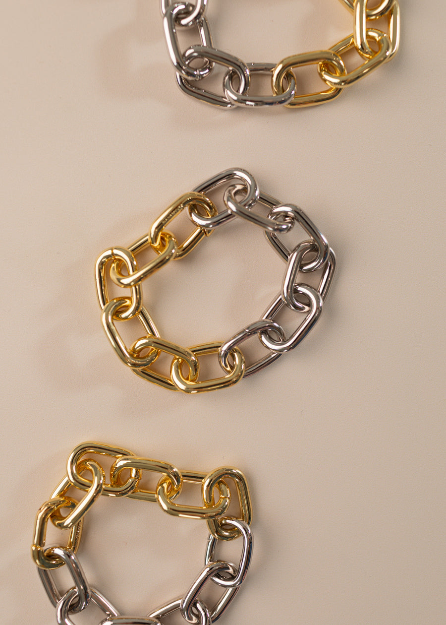 Photo of three link bracelets, half silver half gold on a peach background