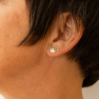 Close-up of model earlobe with a half moon earring and triple ball bar stud