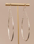 crescent-shaped earring with chain link accents hanging on a gold earring holder