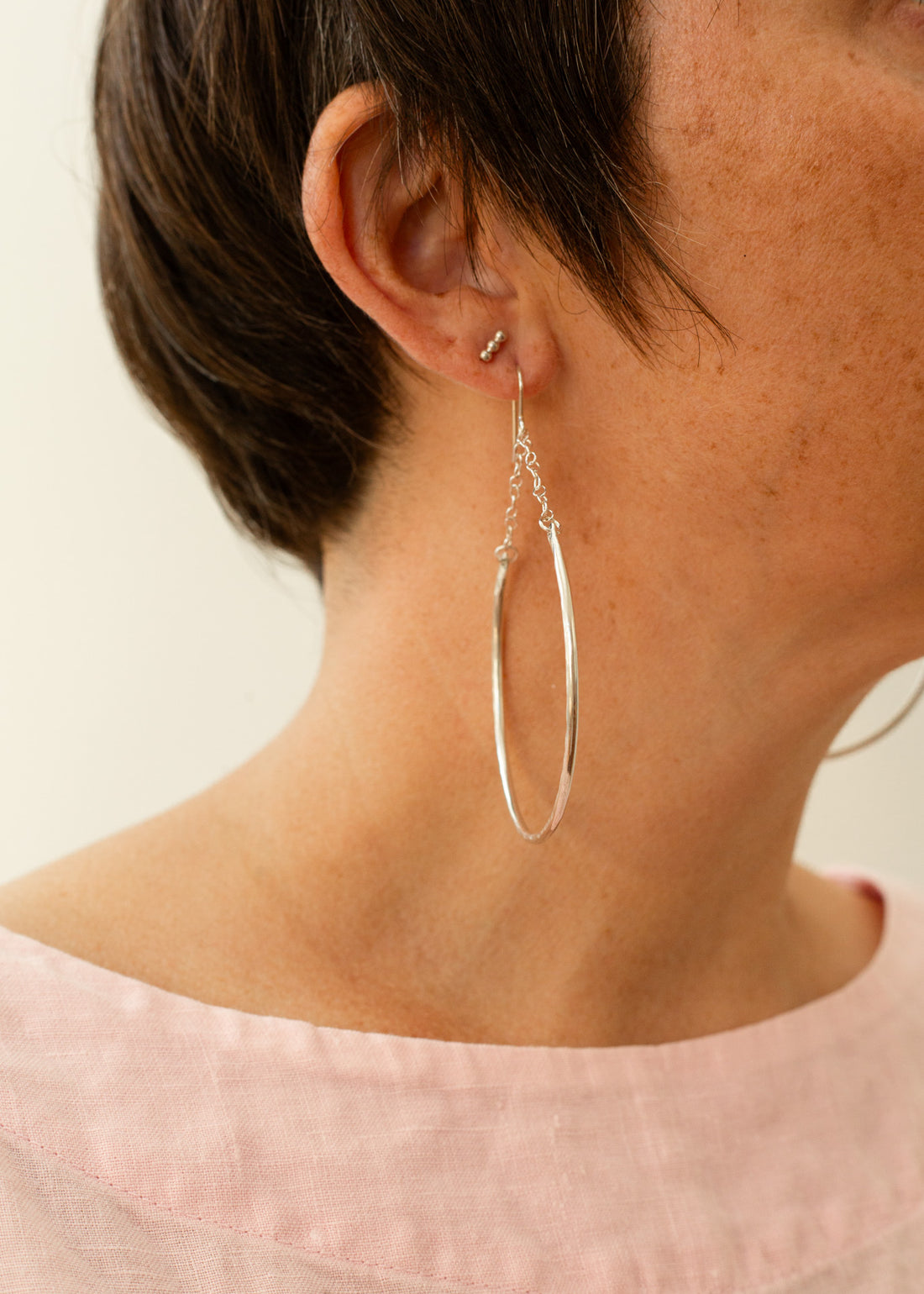 crescent-shaped earring with chain link accents hanging on a models ear