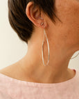 crescent-shaped earring with chain link accents hanging on a models ear
