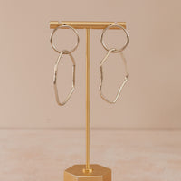 Sterling silver hoop with an organic shape hoop attached, hanging on an earring holder