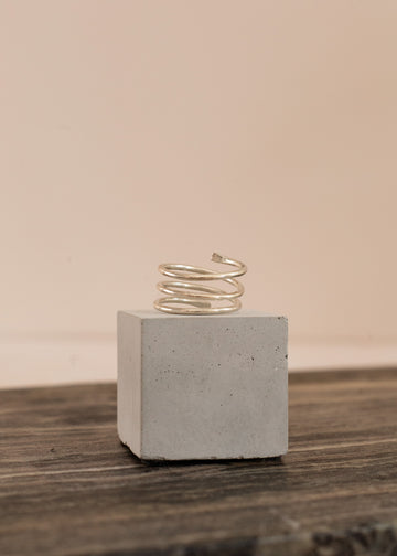 Sterling Silver Ring shaped like coil on a gray cement square