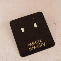 flat-lay of semi-circle silver studs on a black jewelry card