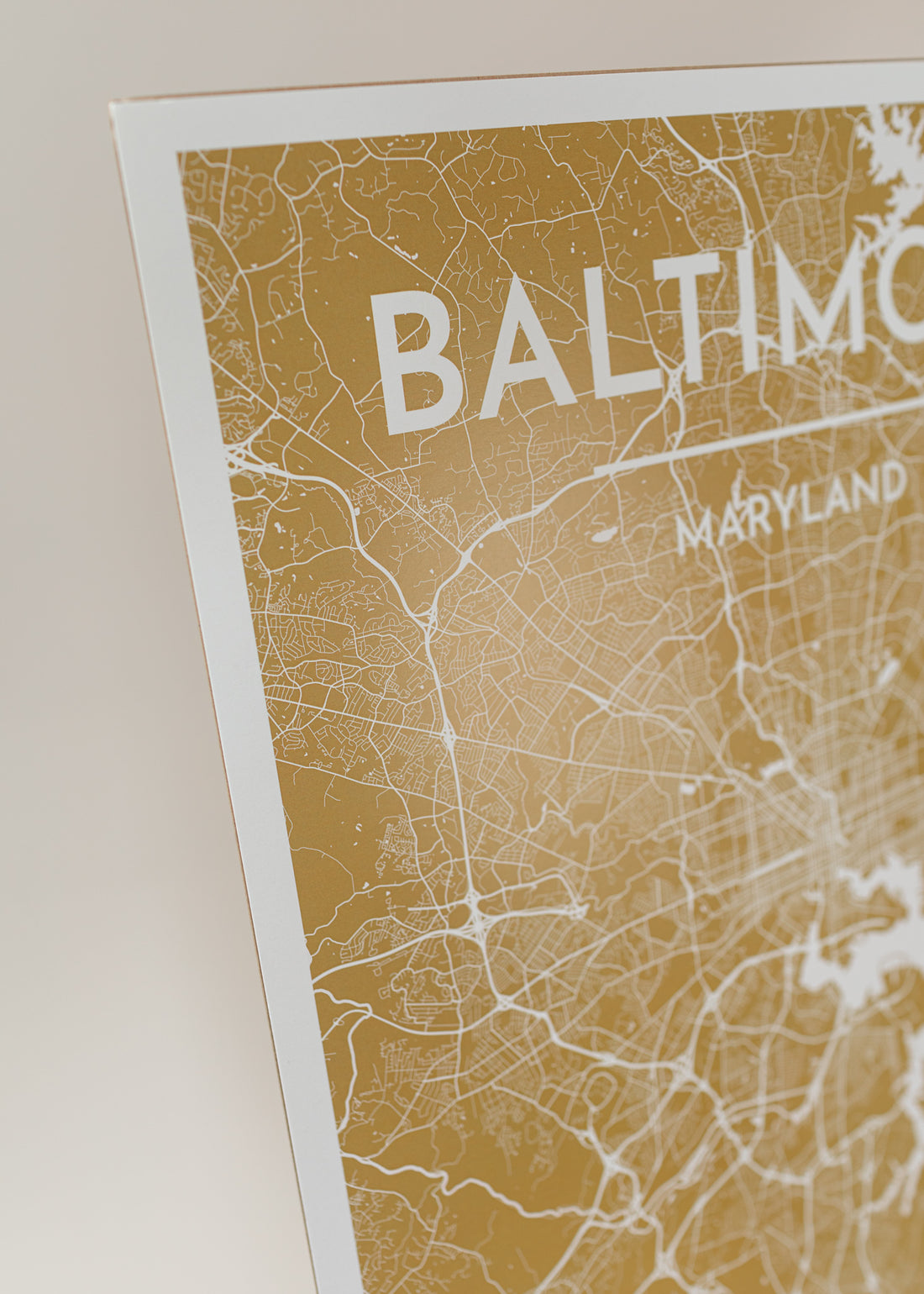 Close-up of golden yellow print map of baltimore with a light pink background