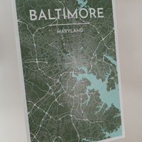 Print of Baltimore map in sea green color, on an art easel with a light pink background