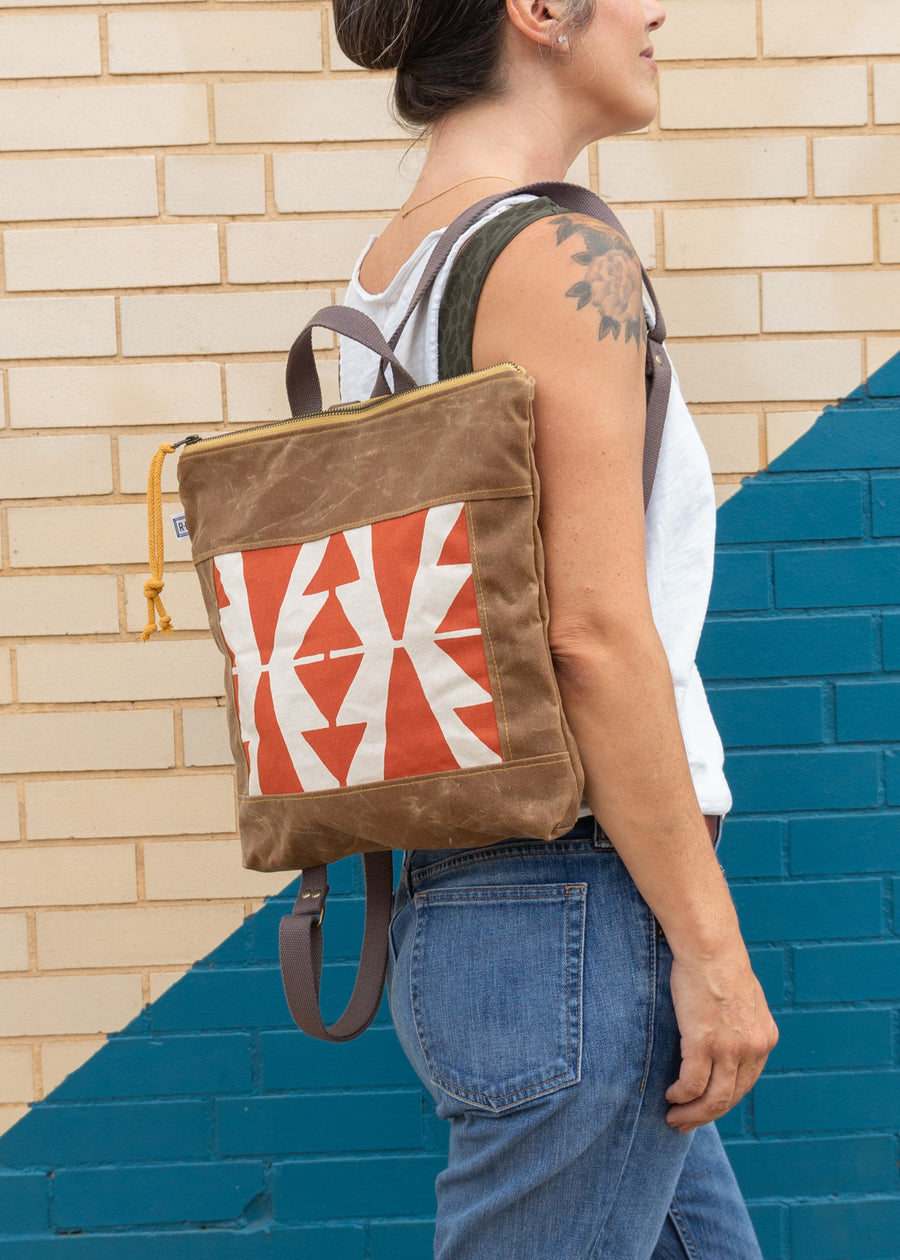 Woman holiding a vegan leather square-shaped backpack on her right shoulder