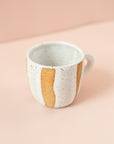 Ceramic mug with white glaze around the mug, with hints of original clay color showing. 