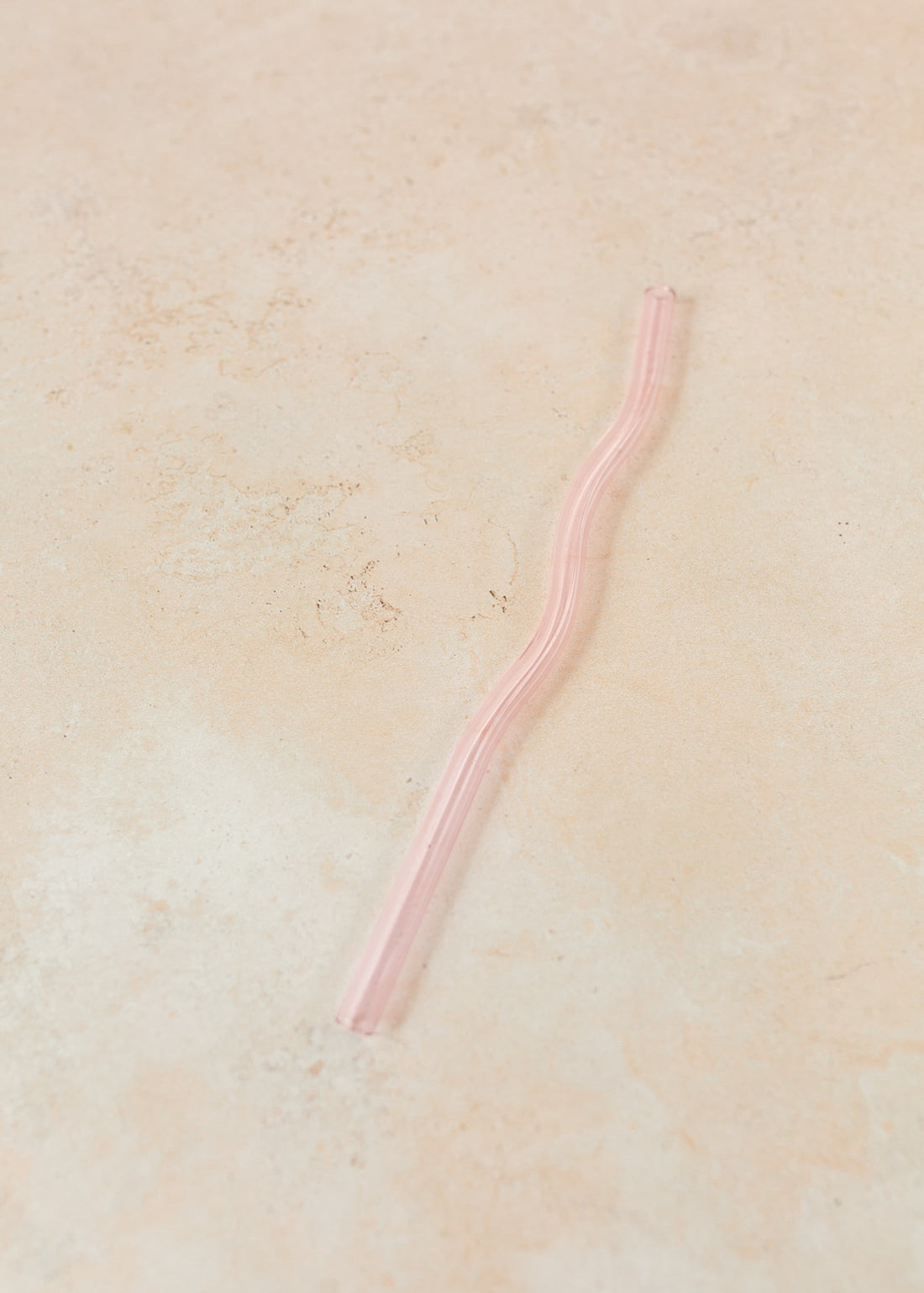 Flatlay of a pink wavy reusable straw. 