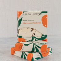 Two boxes of shower steamers with one standing up on top. Boxes are white, orange and green and "Mandarin Patchouli" scented