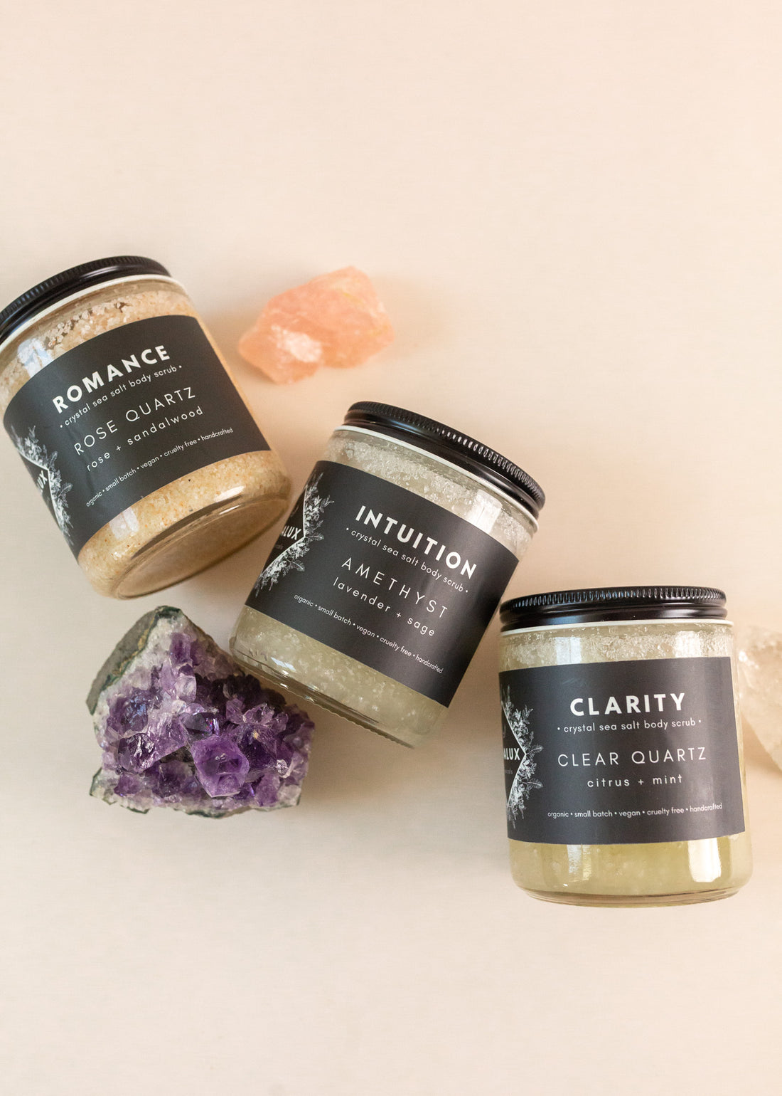Three sea salt body scrub jars on a flatlay with crystals lying around them