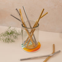 glass of silver and gold variety of reusable straws