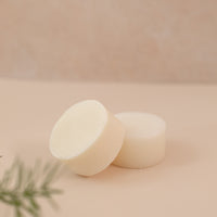 Photo of a shampoo and conditioner bar on a light pink backdrop