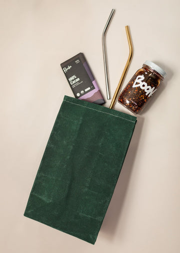 Emerald Eco-Friendly Lunch Bag with Boon Sauce, two reusable straws and Raaka Chocolate coming Out From Bag