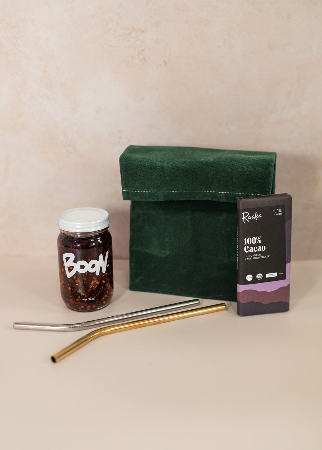 Emerald Eco-Friendly Lunch Bag With Boon Sauce, Raaka Chocolate and Two Reusable Straws laying in front