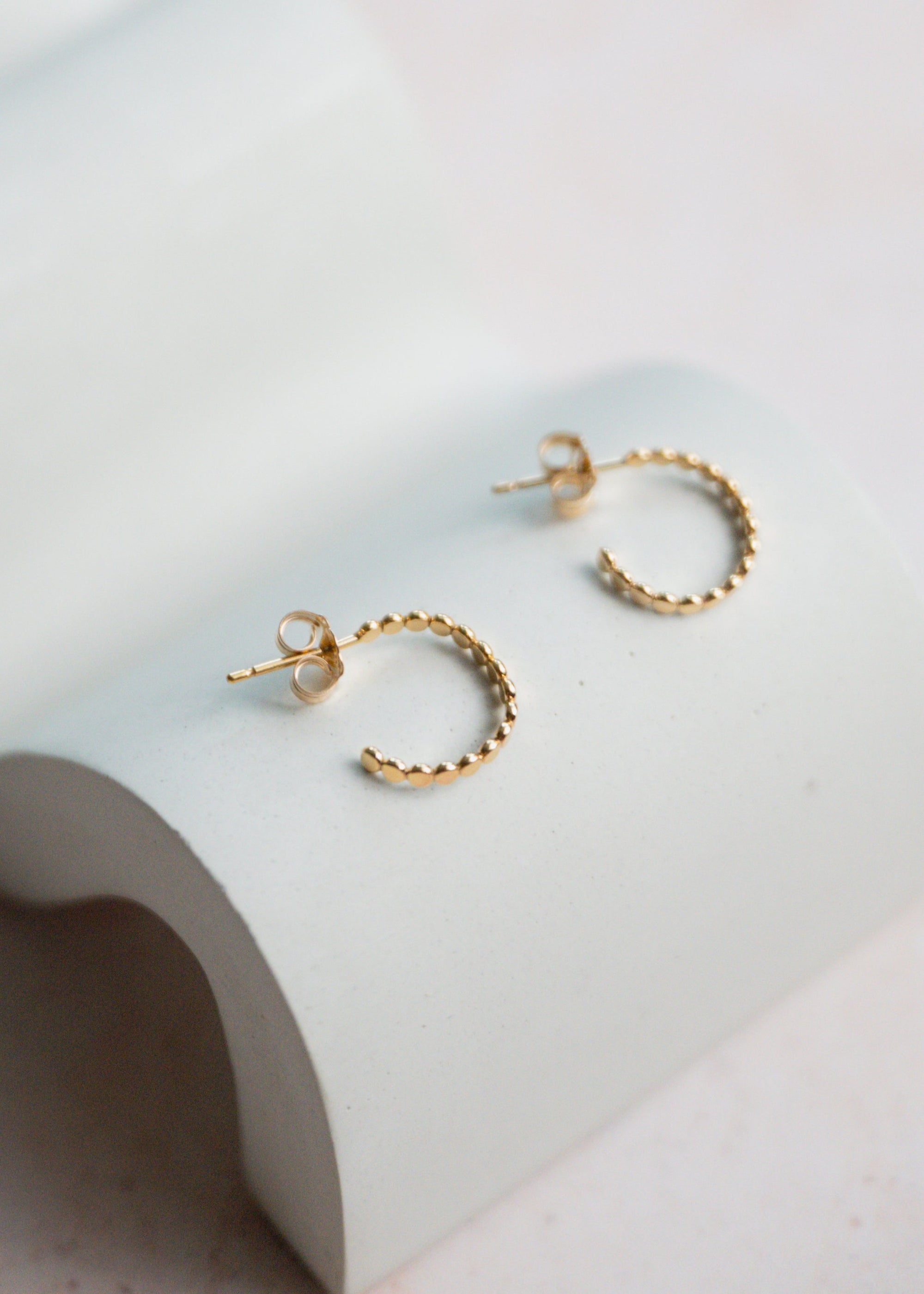 Gold hoop earrings on a light gray surface