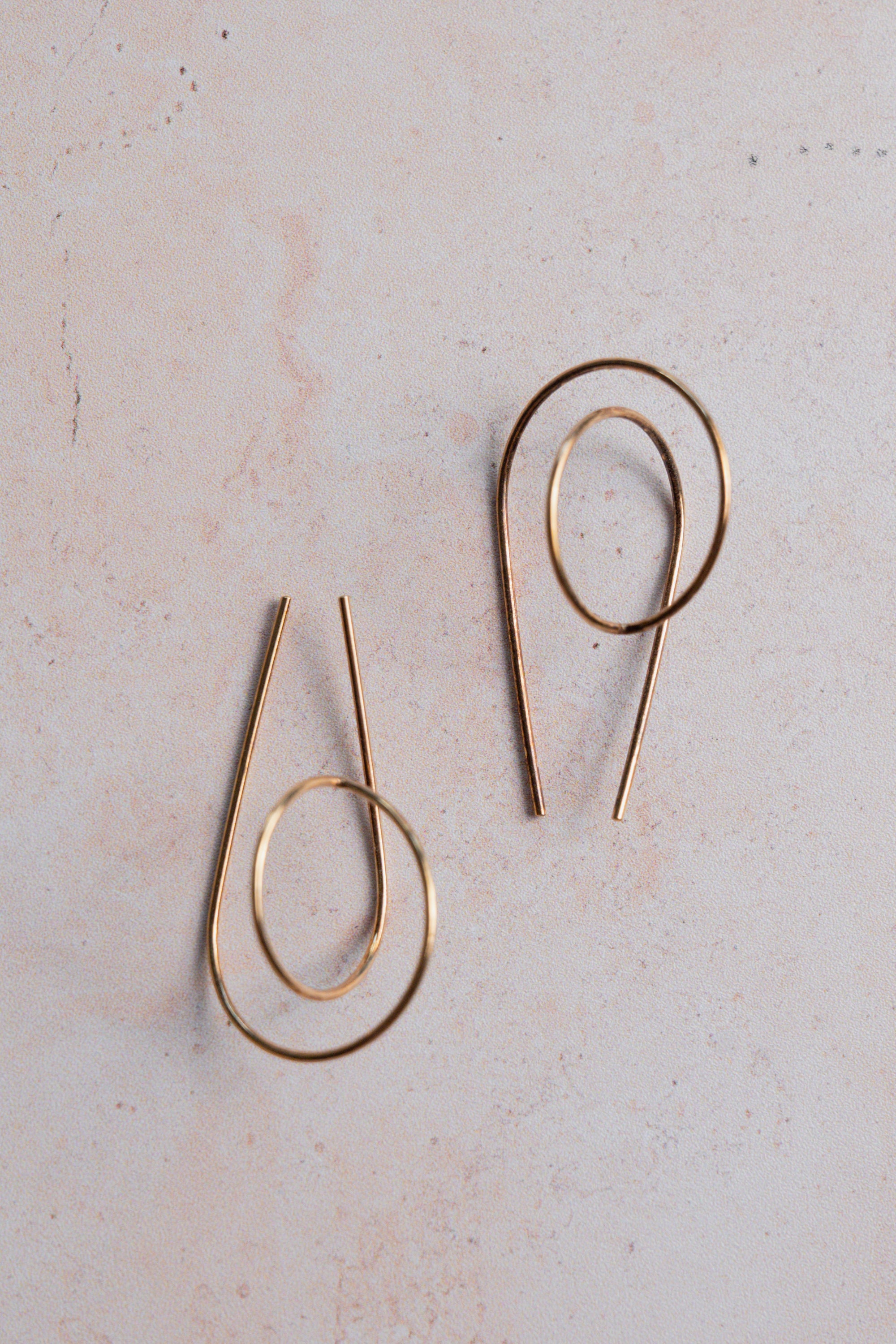 Pair of gold hoop earrings on a light beige background