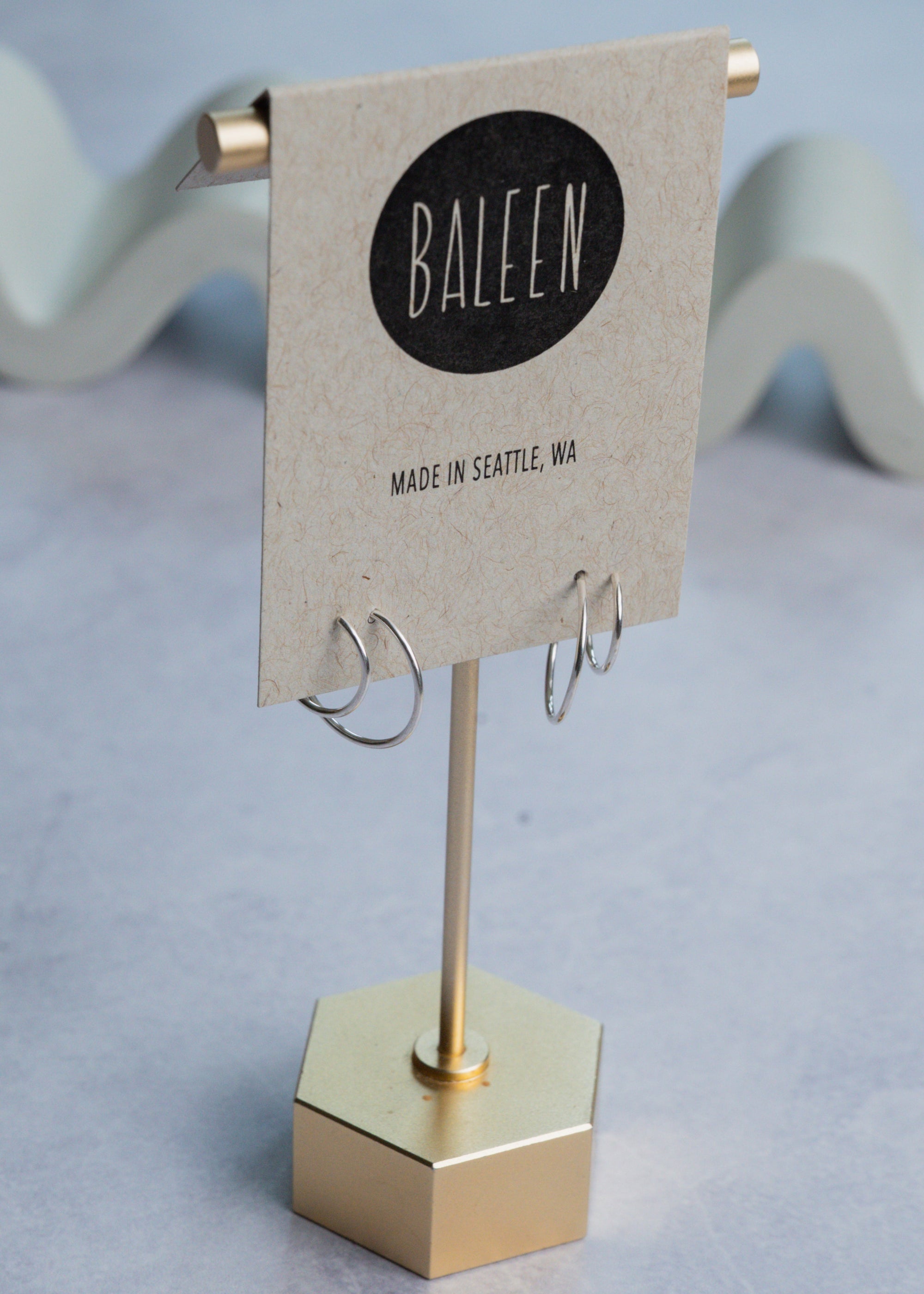 Silver hoop earrings on a 'Baleen' branded card on a light gray background