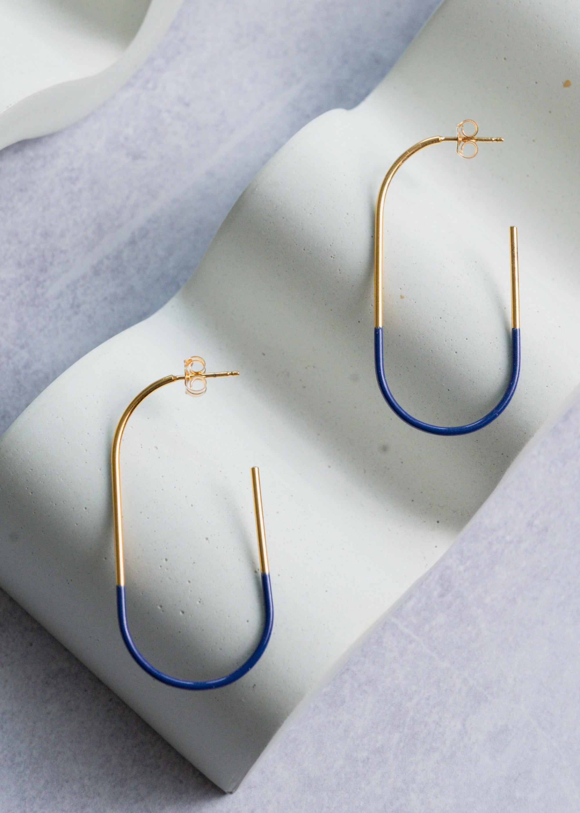 Gold and blue hoop earrings on a light gray surface