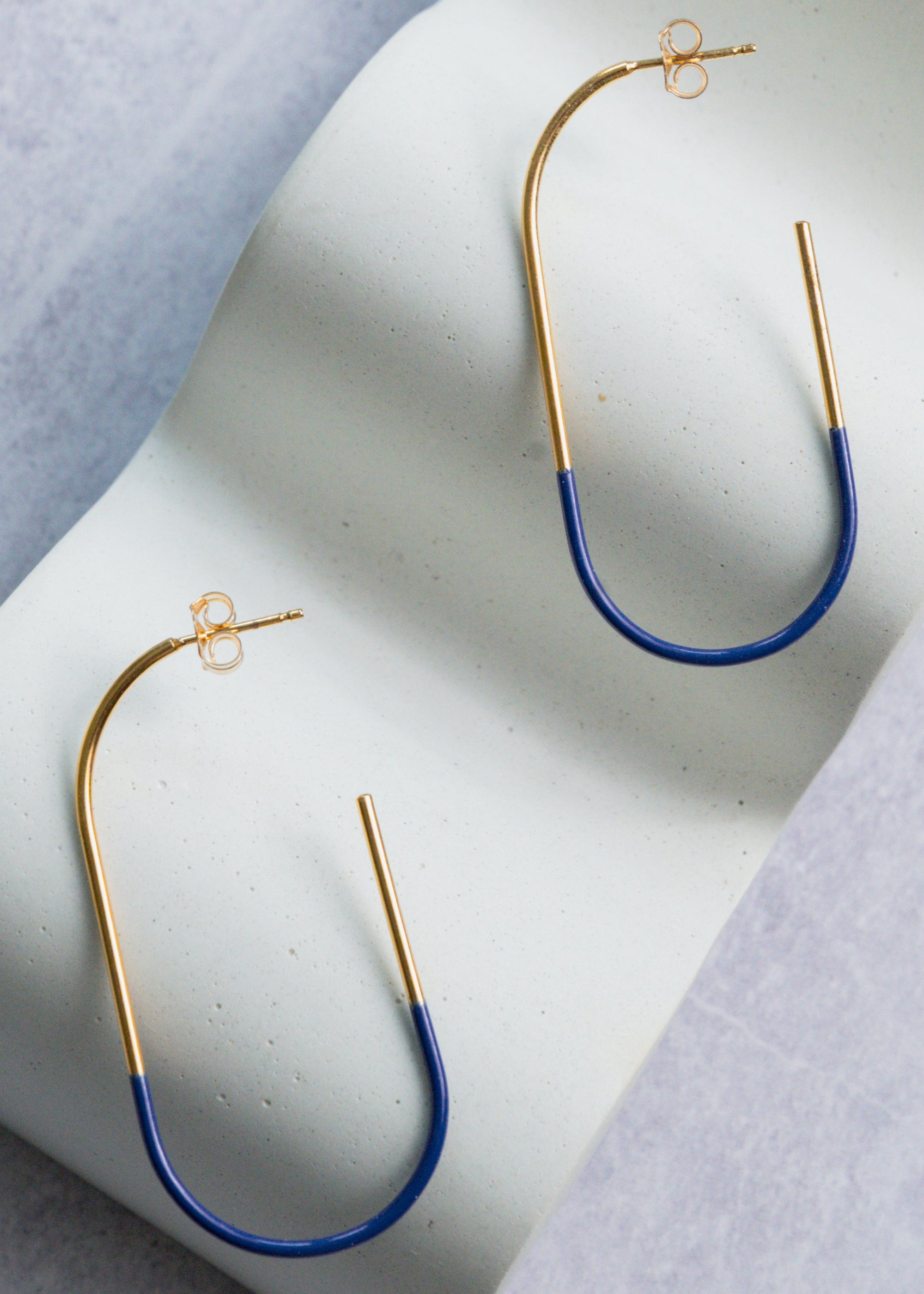 Pair of gold and blue earrings on a textured surface