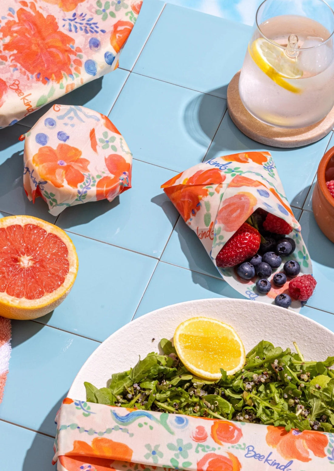 picpic set up with beeswax wraps throughout covering a salad, holding berries and half a grapefruit. 