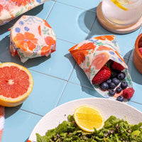 picpic set up with beeswax wraps throughout covering a salad, holding berries and half a grapefruit. 