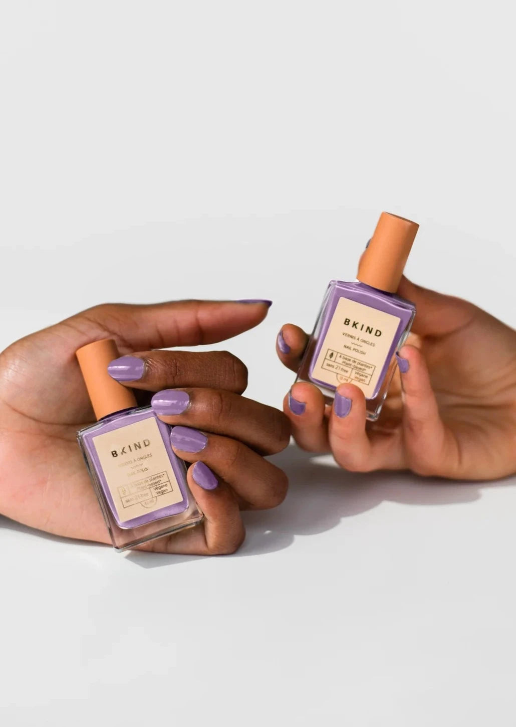 Two Hands Holding Vegan Nail Polish in Purple Hill by BKIND