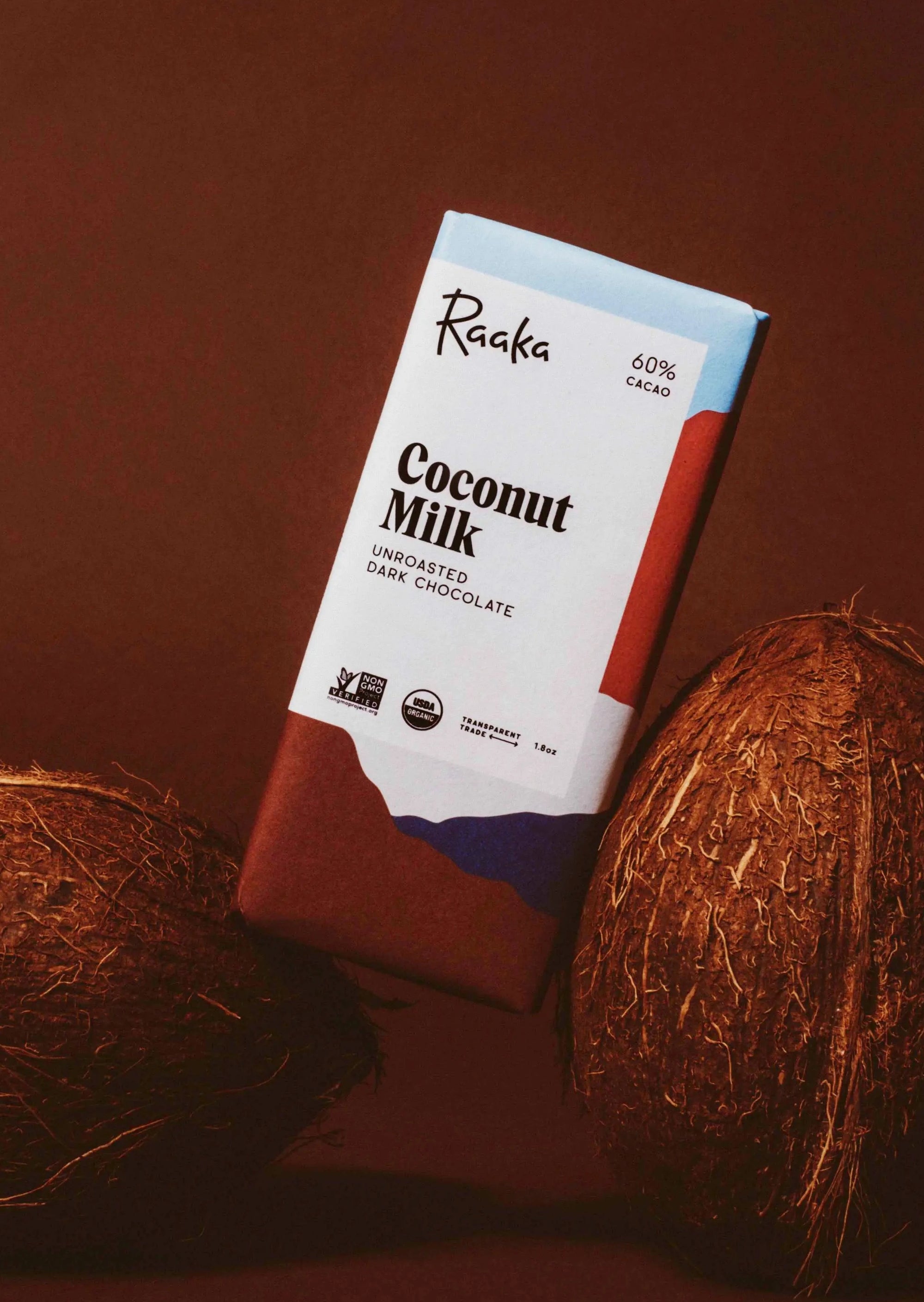 photo of the coconut milk chocolate bar leaning against two coconuts with a brown background