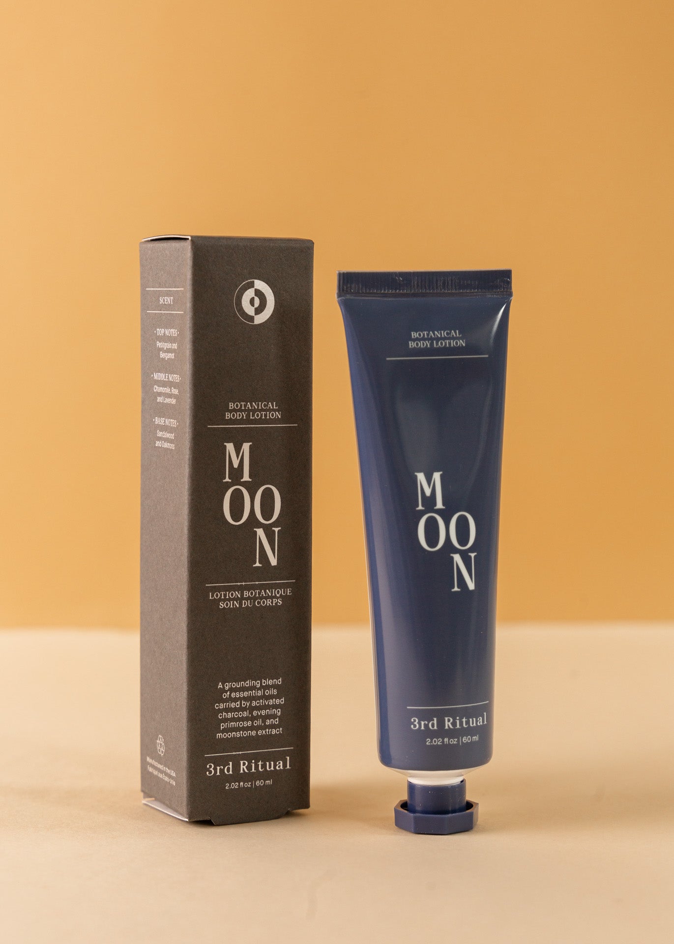 Mini blue tube of botanical body cream in &#39;moon&#39; standing  next to the box it comes in