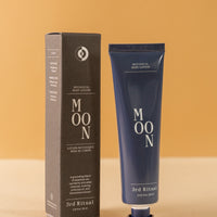 Mini blue tube of botanical body cream in 'moon' standing  next to the box it comes in