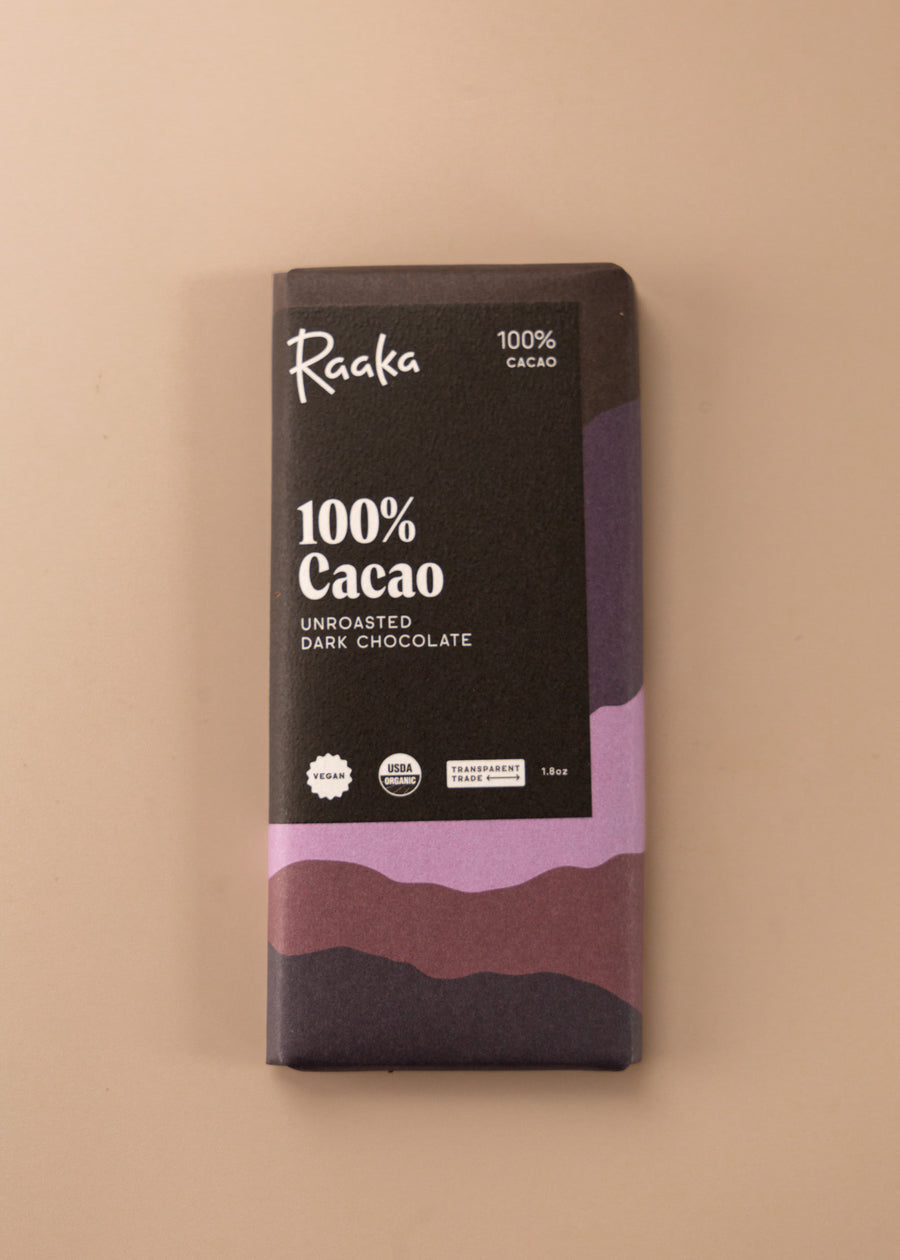 flatlay of a 100% cacao chocolate bar by Raaka. Cover is layers of colors in a variety of browns, pinks and deep purple.