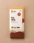 flatlay of an unroasted dark chocolate bar ‘oat milk’ by Raaka. Cover is layers of colors in a variety of cream, browns and orange