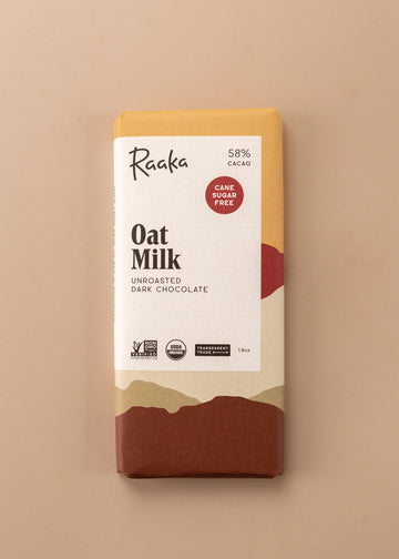 flatlay of an unroasted dark chocolate bar ‘oat milk’ by Raaka. Cover is layers of colors in a variety of cream, browns and orange