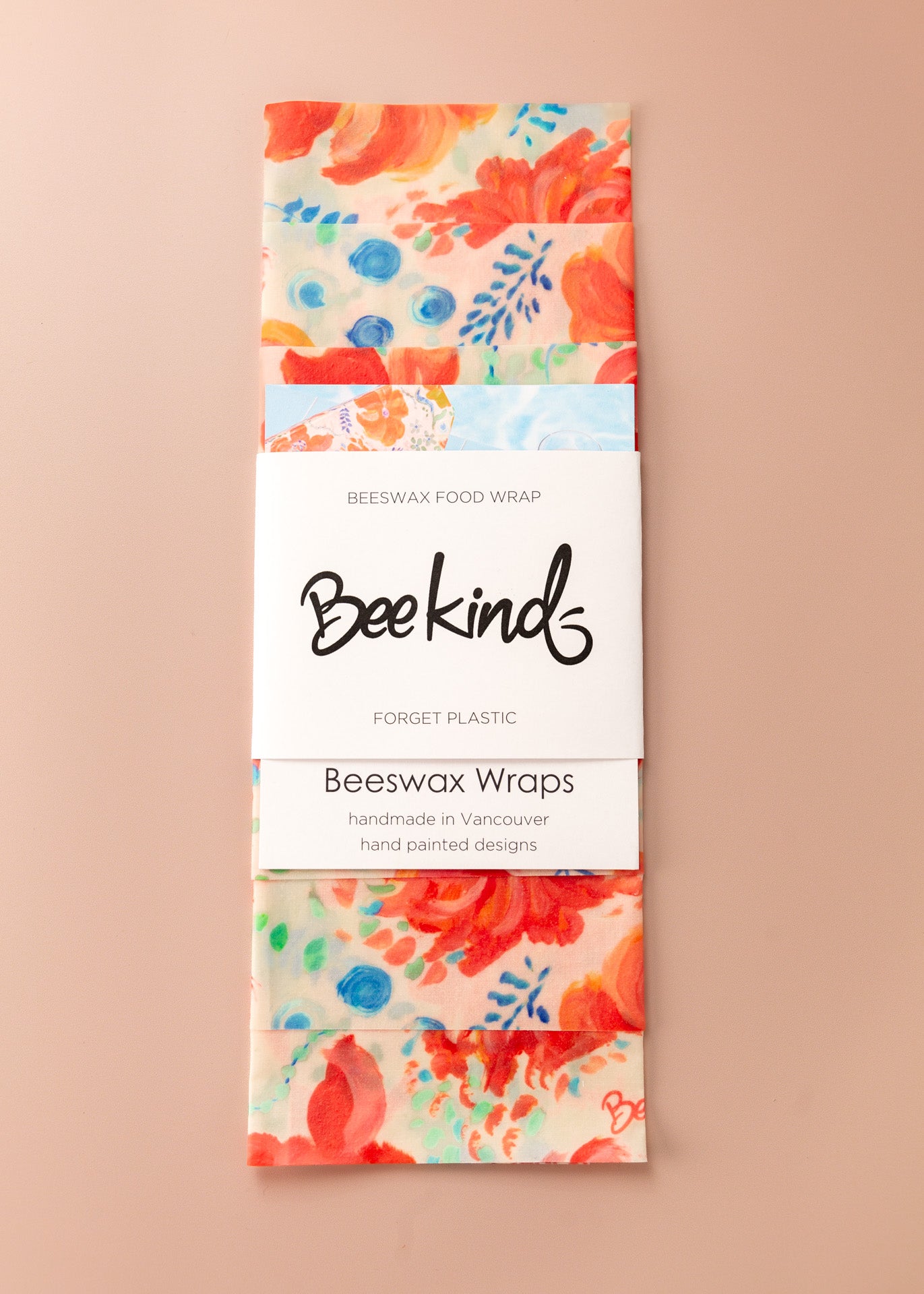 Set of 3 beeswax wraps folding with a white label saying "beekind" on a pink flatlay