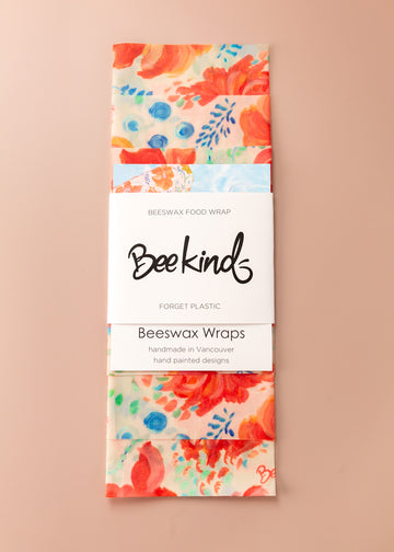 Set of 3 beeswax wraps folding with a white label saying "beekind" on a pink flatlay