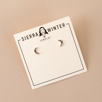 flatlay of a jewelry card stating "sierra winter jewelry" with two crescent moon silver studs on it.