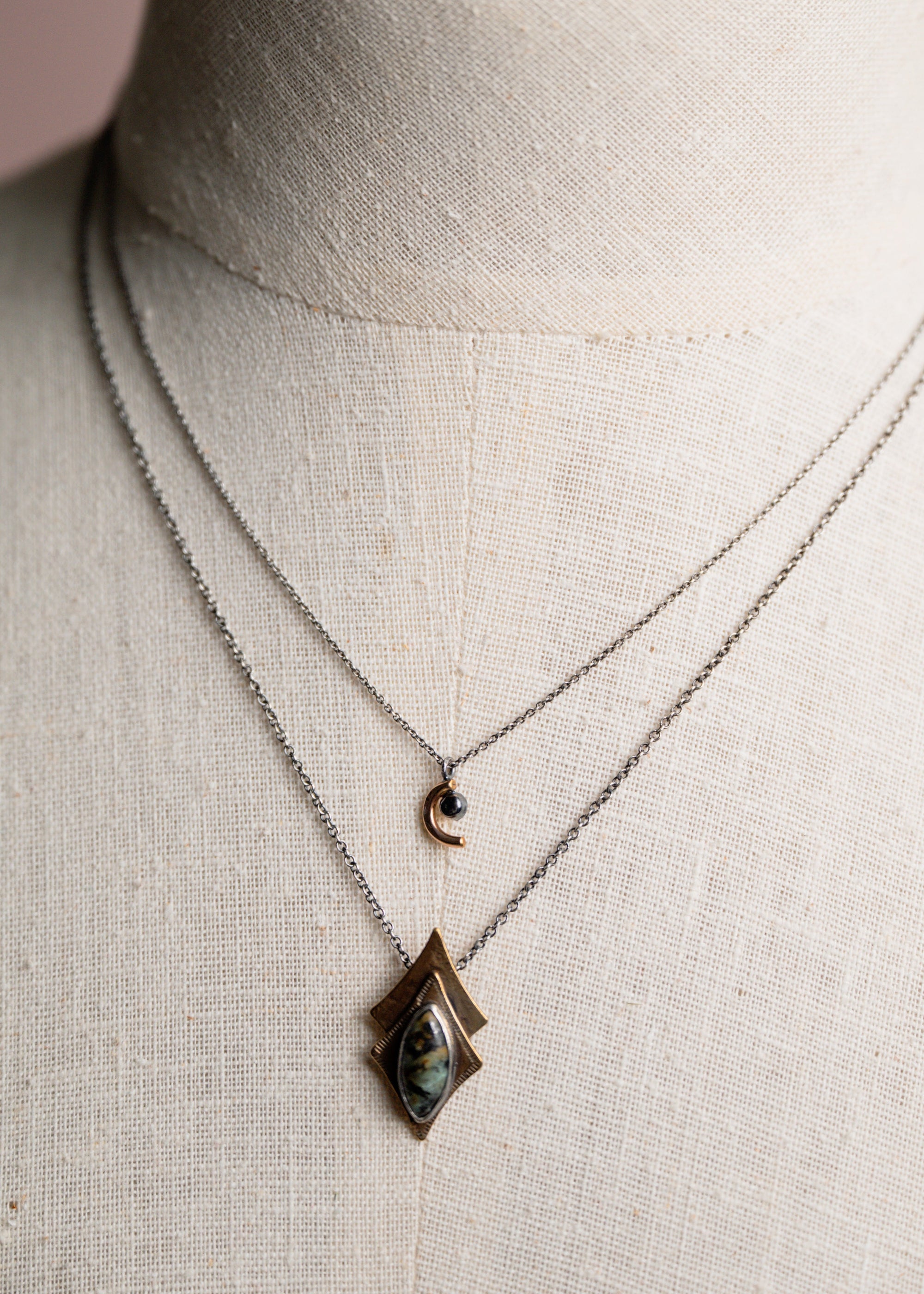 Necklace with a pendant on a mannequin against a pink background