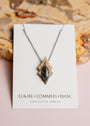 Necklace by 'Claire Sommers Buck' against a natural wood background