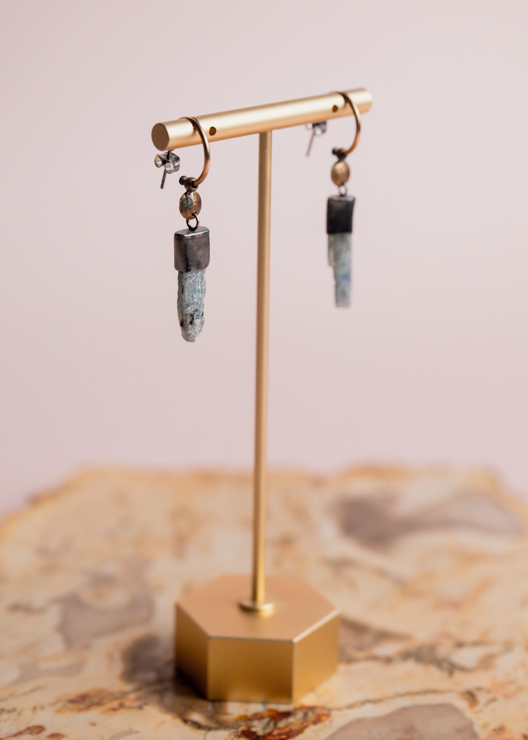 Gold and silver Akh earrings by Claire Sommers Buck shown on a jewelry stand