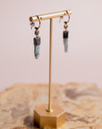 Gold and silver Akh earrings by Claire Sommers Buck shown on a jewelry stand