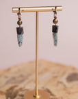Gold and silver Akh earrings by Claire Sommers Buck shown on a jewelry stand