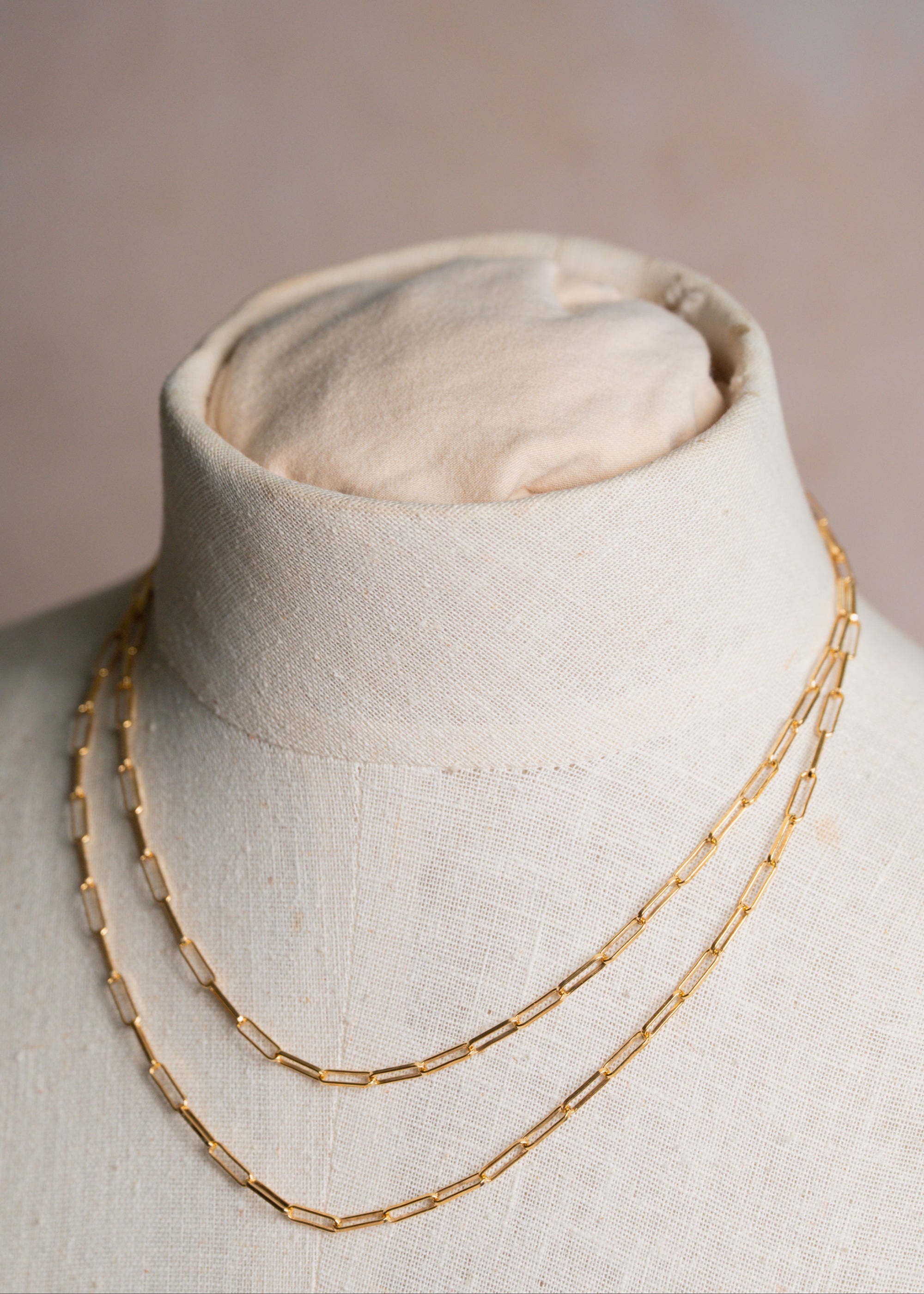 Gold chain necklace on a mannequin bust with a neutral background