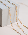 Close up of gold link chain necklaces by Gwen Beloti layered over concrete block display