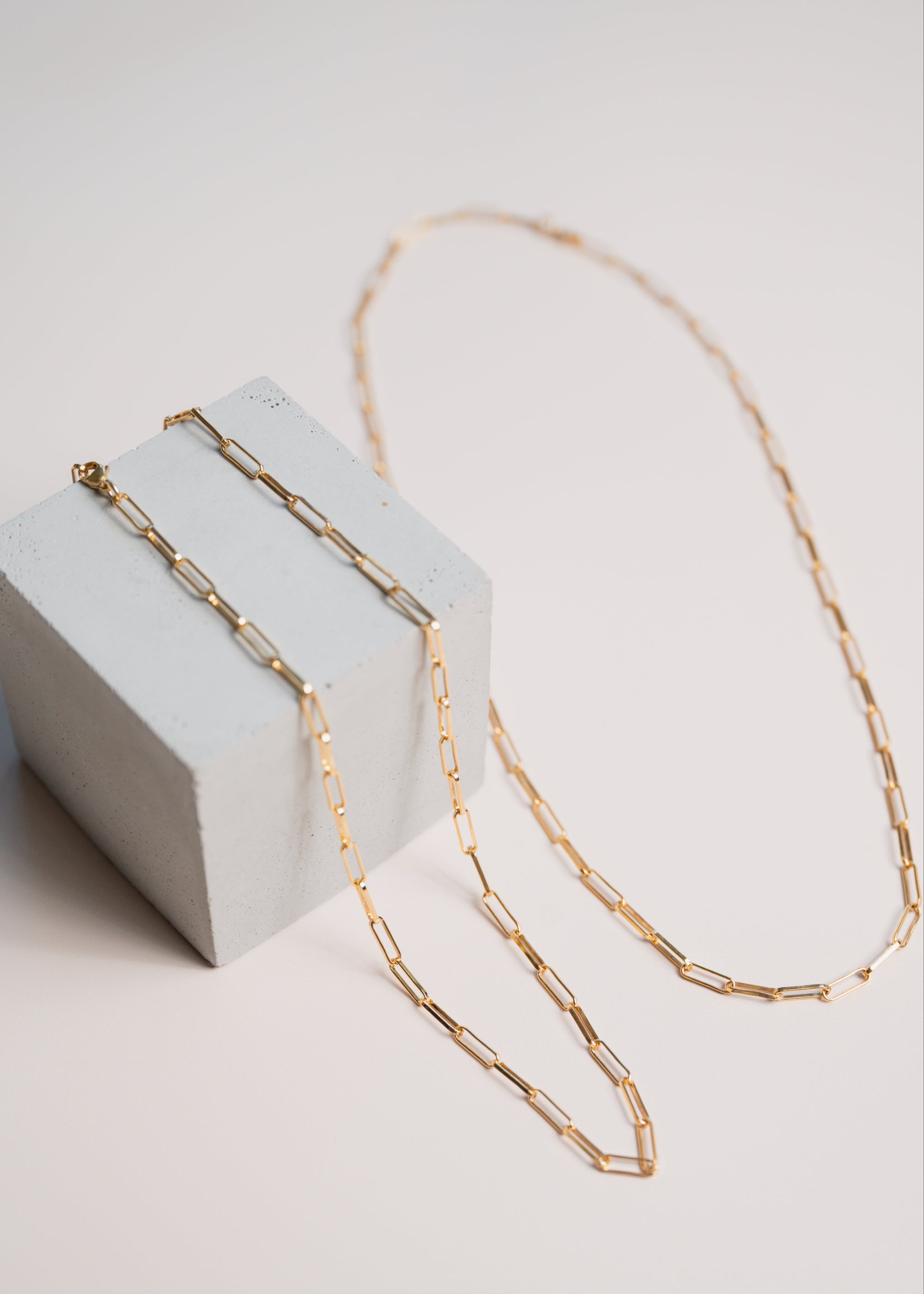 Gold link chain necklaces by Gwen Beloti layered over concrete block display
