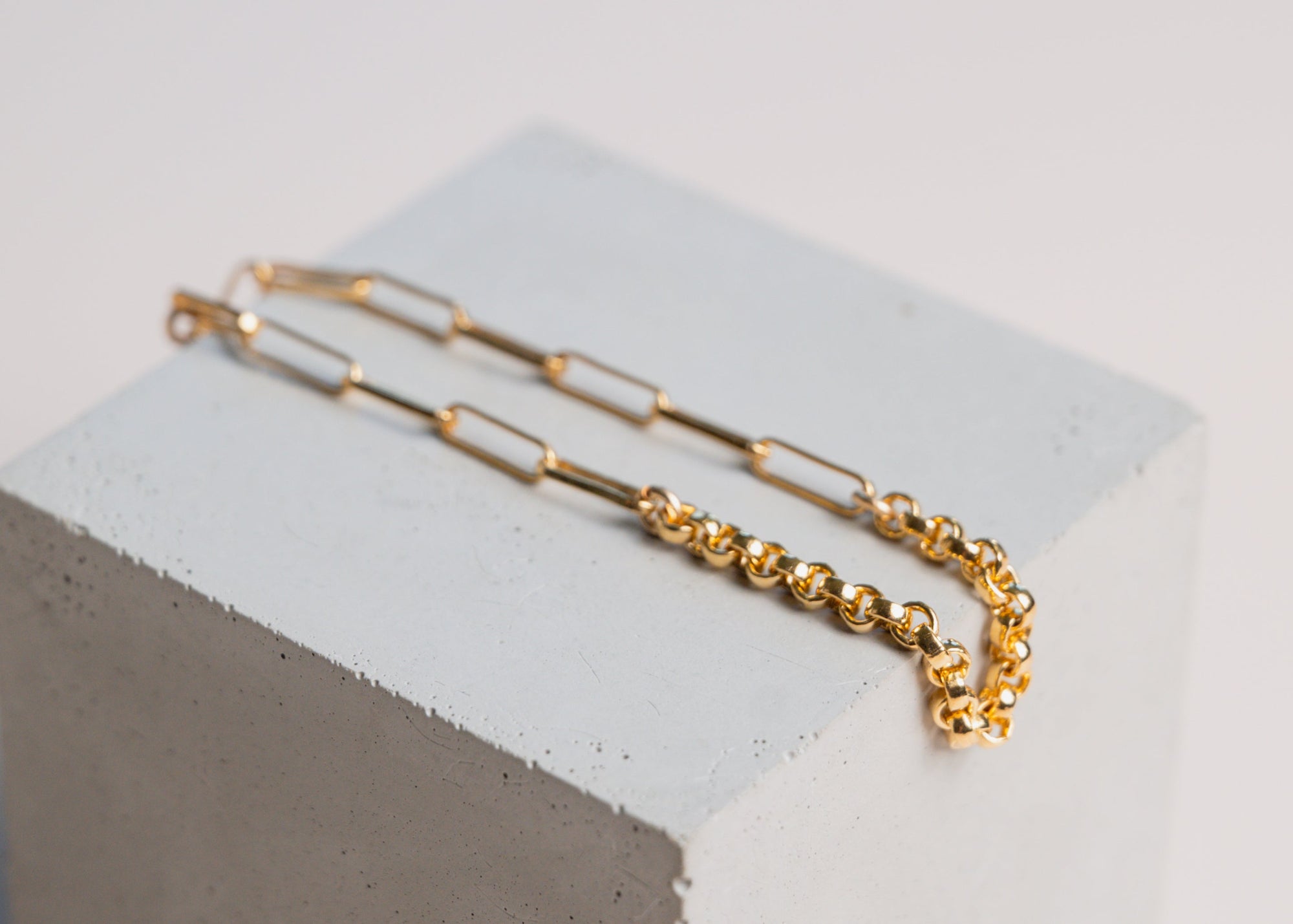 Gold two chain bracelet by gwen beloti on a light gray cube