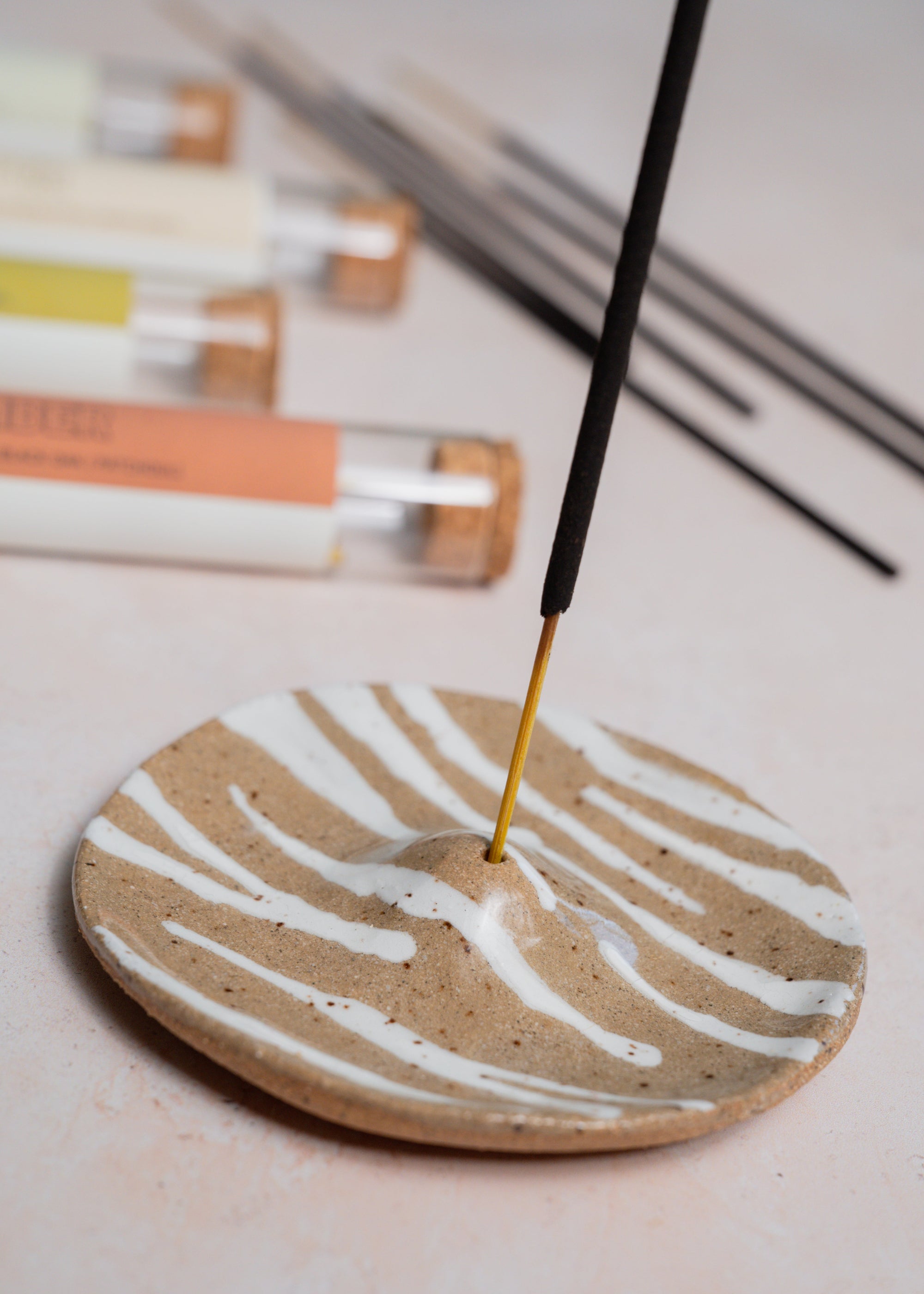Incense stick burning on a ceramic dish with soft focus background