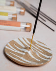 Incense stick burning on a ceramic dish with soft focus background
