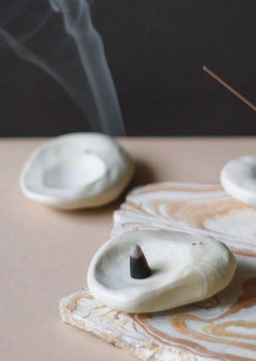 A charcoal incense cone smoking on an incense holder