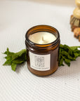 close up of a candle labeled "meadow stars" with mint besides the candle on a white background