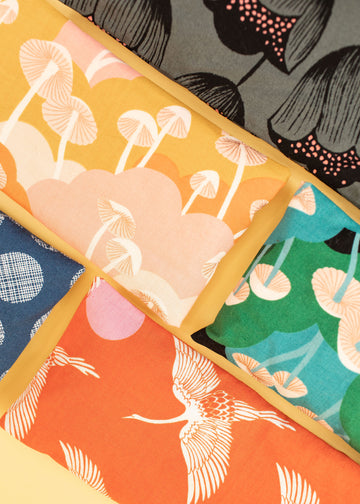 flat lay of a variety of eye pillows ranging from mushroom illustrations, flowers, and birds